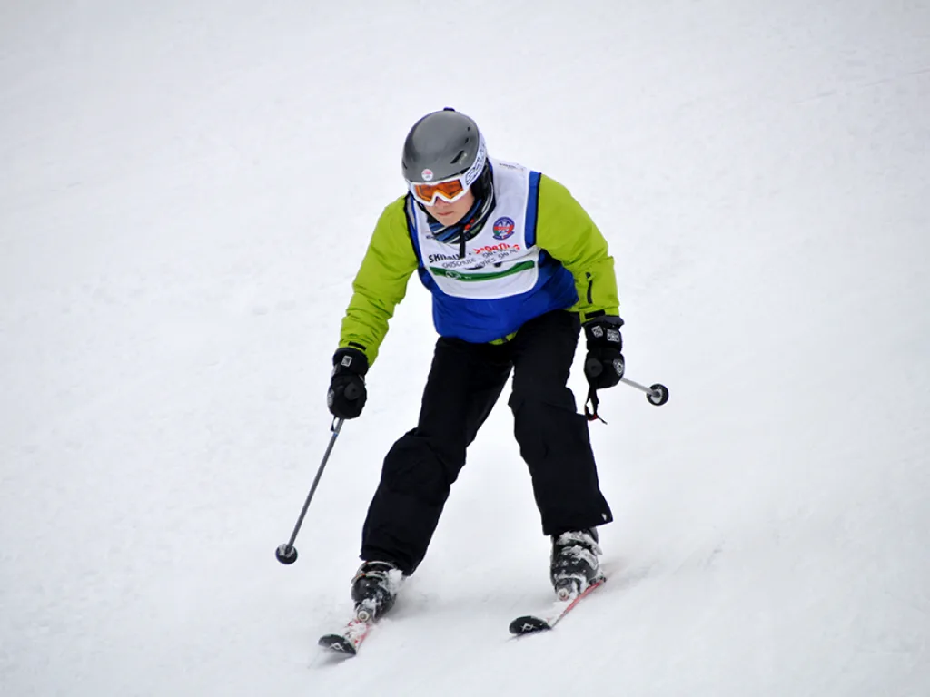 Skifahrer in gelber Jacke fährt zügig talwärts.